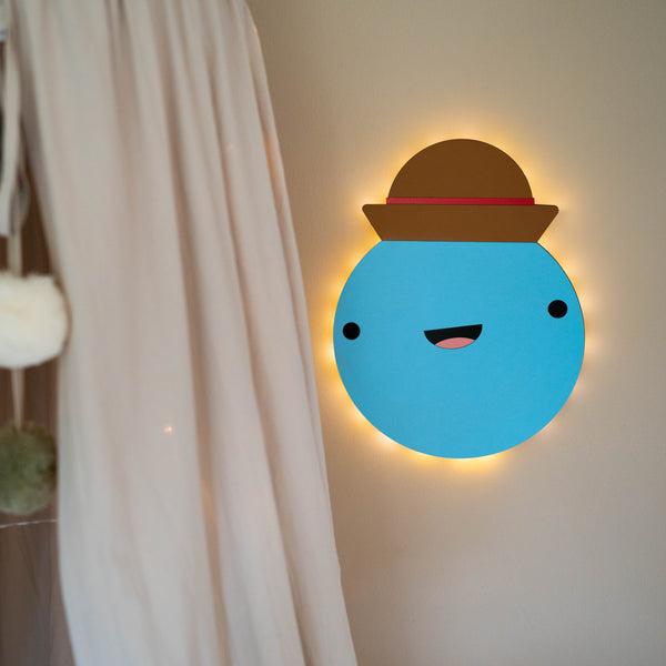 Sengelampe til børn: blå væglampe med hat på, og lampen lyser 